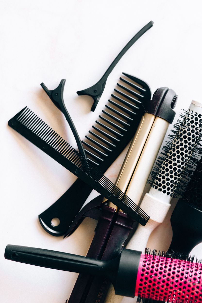 Hair styling brushes and combs arranged on a pale surface